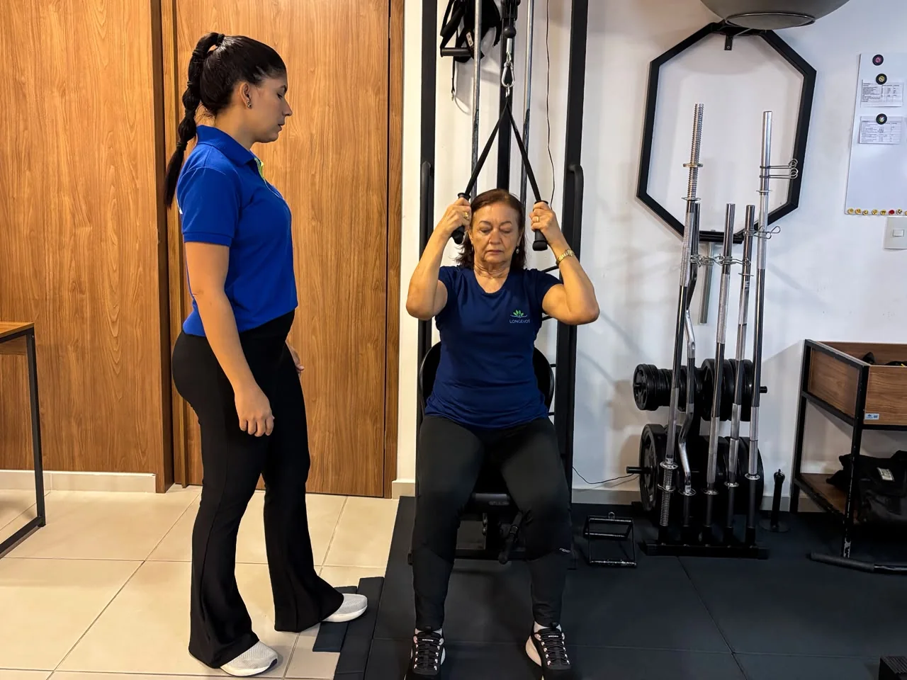 Profissional acompanhando uma aluna durante exercício no estúdio